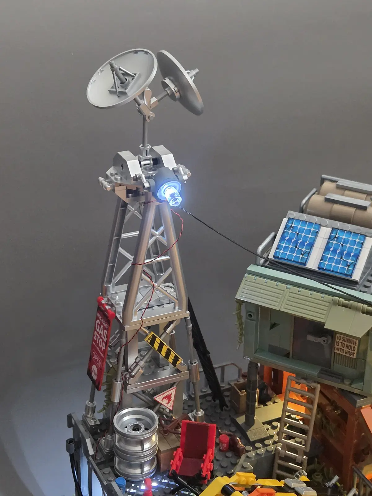 Silver communications tower with satellite dishes and blue spotlight