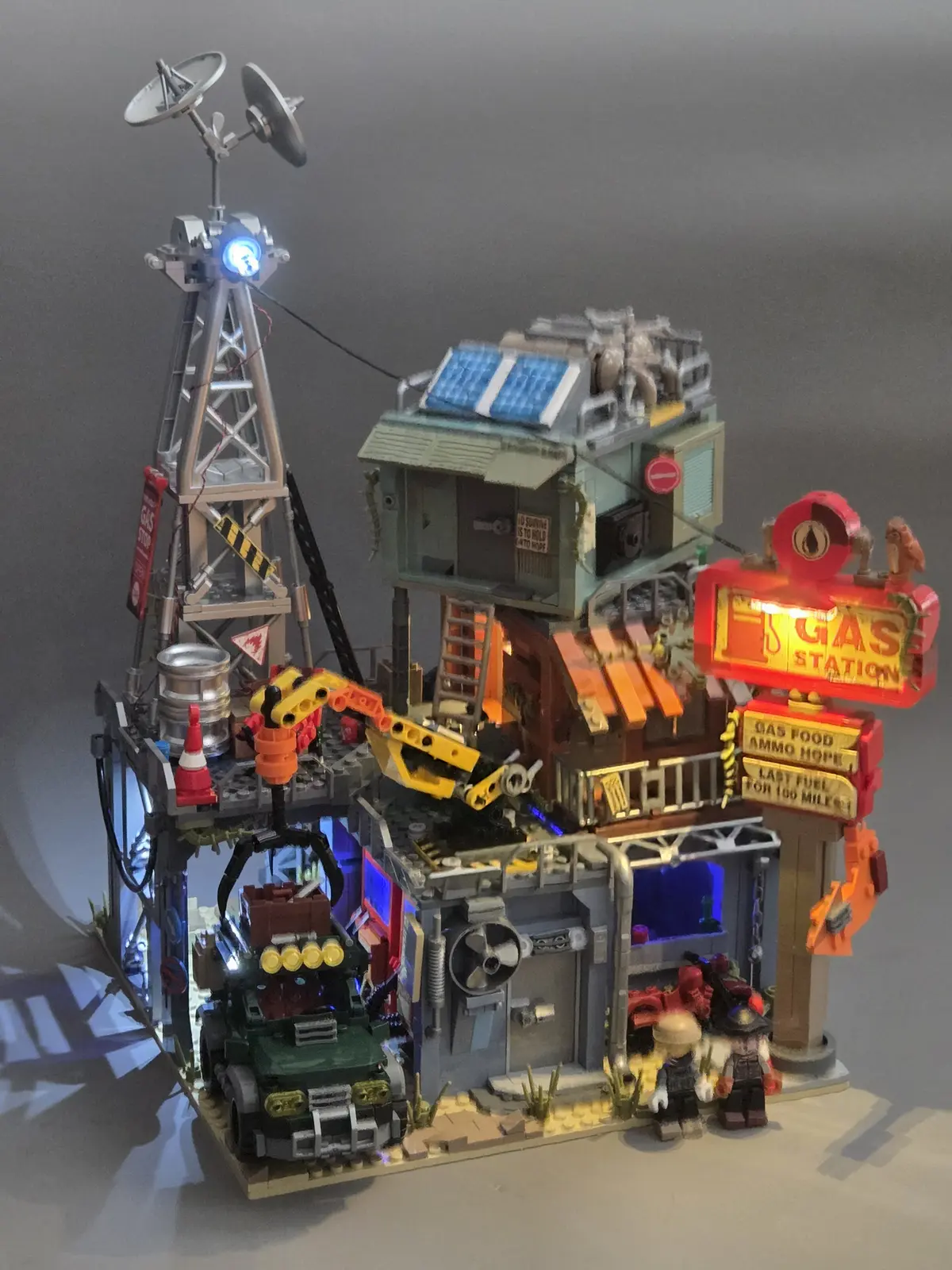 Completed IAMBRICK Doomsday Gas Station illuminated with blue and warm interior lights